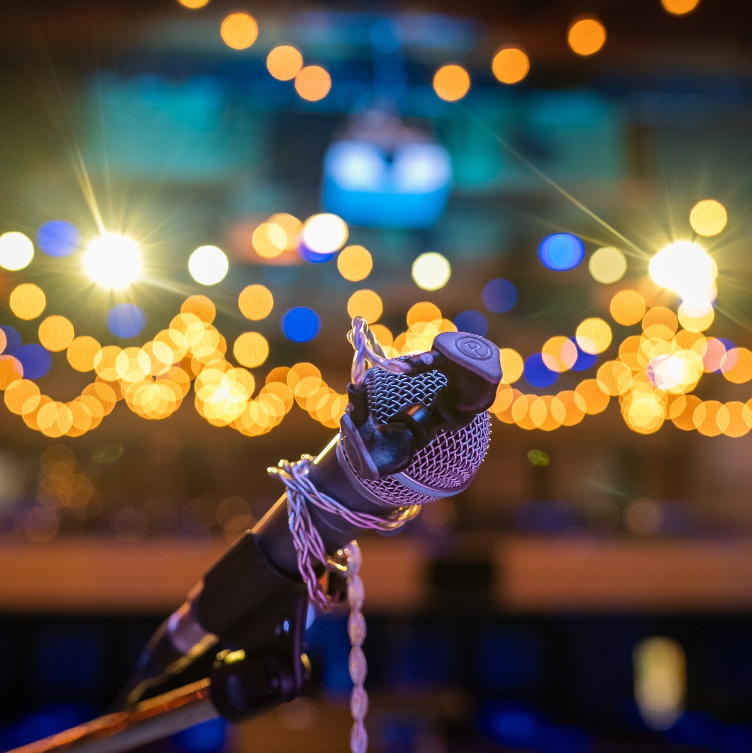 IEMs and cord wrapped around a mic with lights in the background.