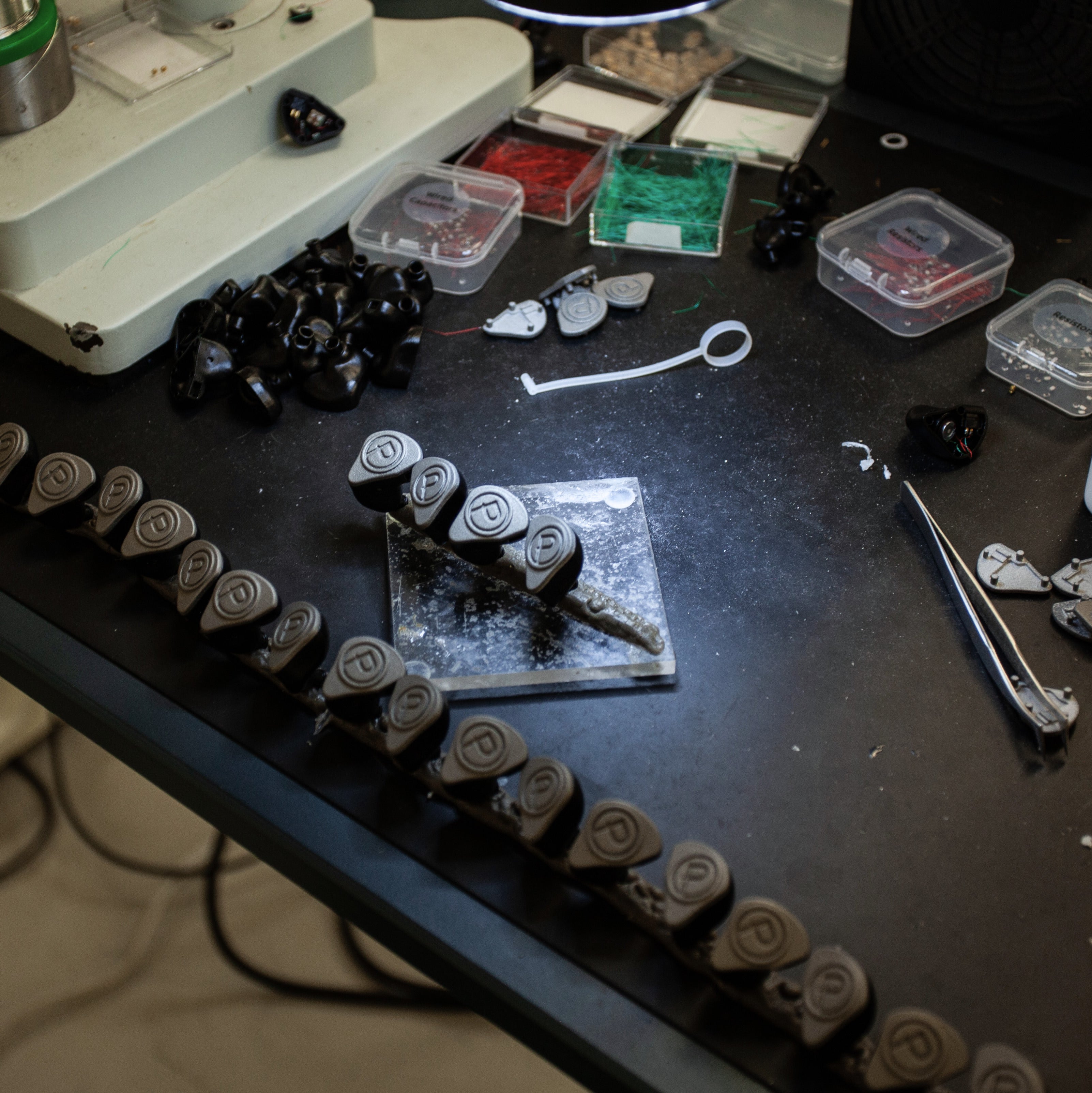 Black table with materials scattered to build IEMs.