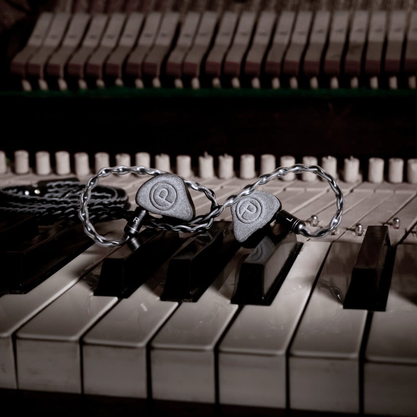Unity IEMs resting on piano keys in dim lighting.