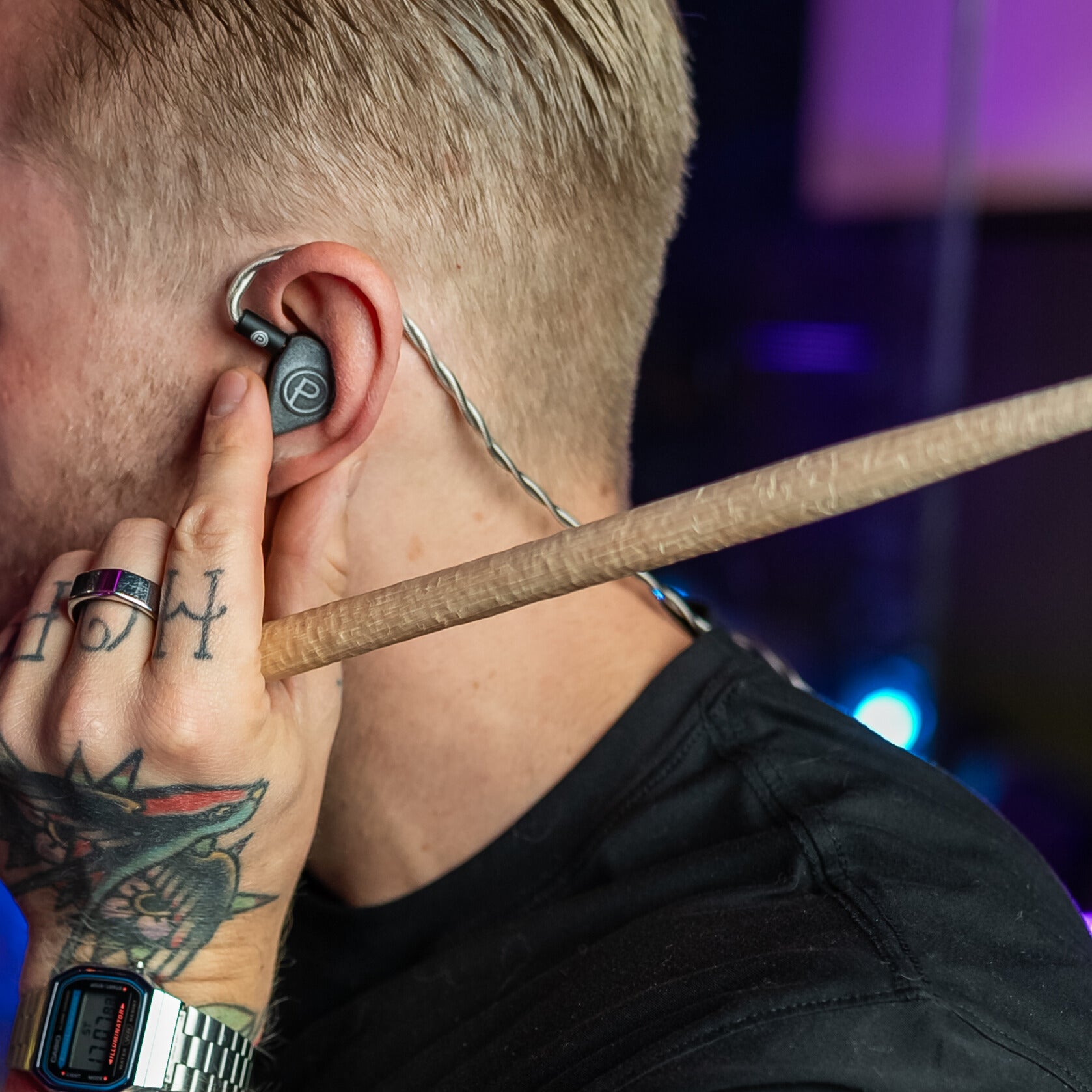 Man inserting Plunge Audio IEM into ear holding drum stick.