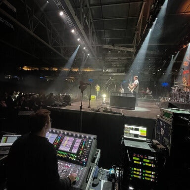 Audio engineer side-stage at the console during a concert.