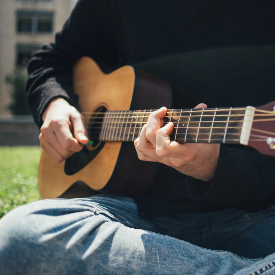Playing guitar in the park cross-legged.