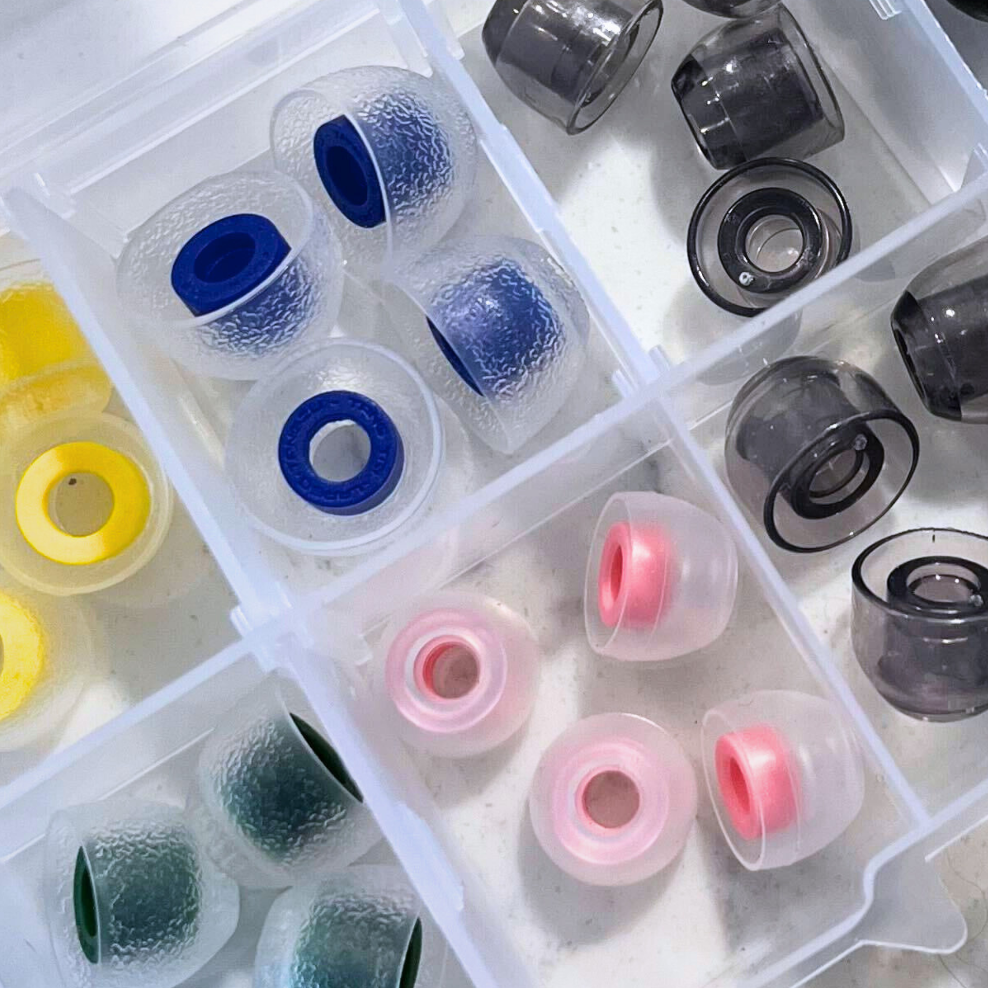 Close-up of coloured IEM silicone tips in a clear case.