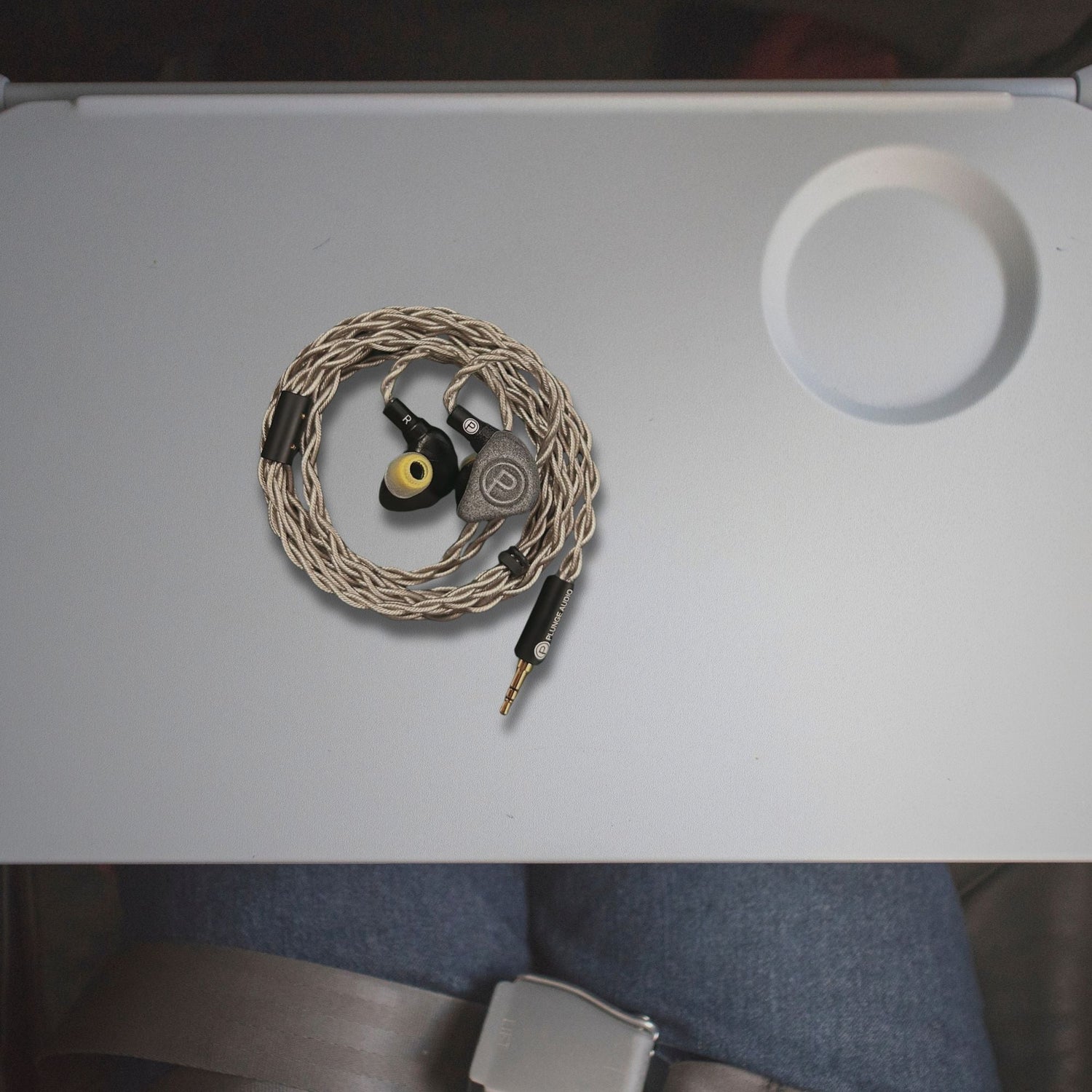 Plunge Audio IEMs resting on airplane seat tray.