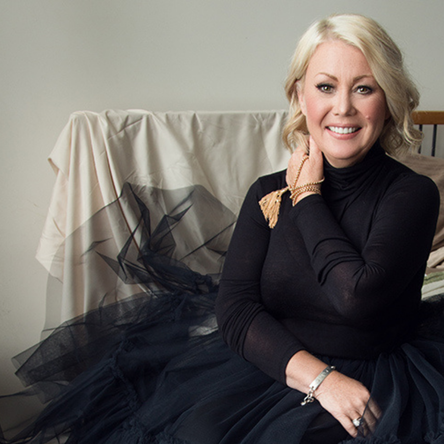 Jann Arden dress in a black tulle dress sitting.