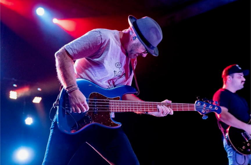 Shane Hendrickson wearing IEMs and playing electric guitar during live performance.