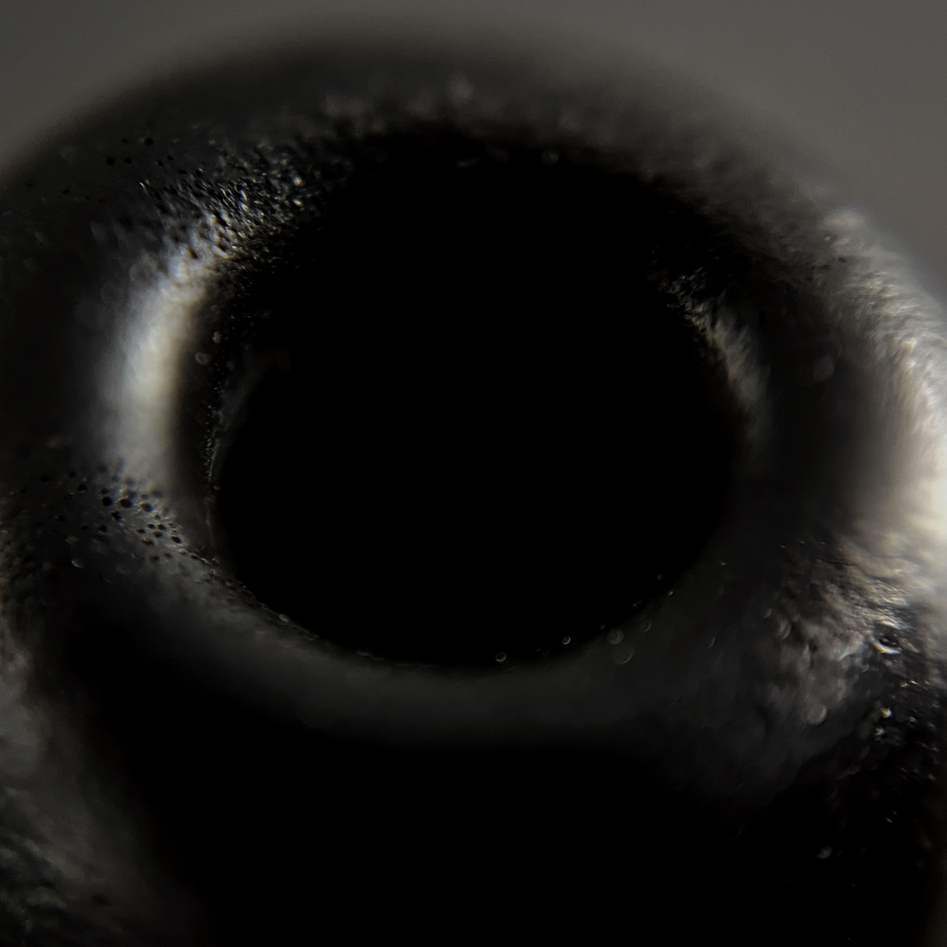 Close-up of a black, textured IEM tip with a central circular feature.
