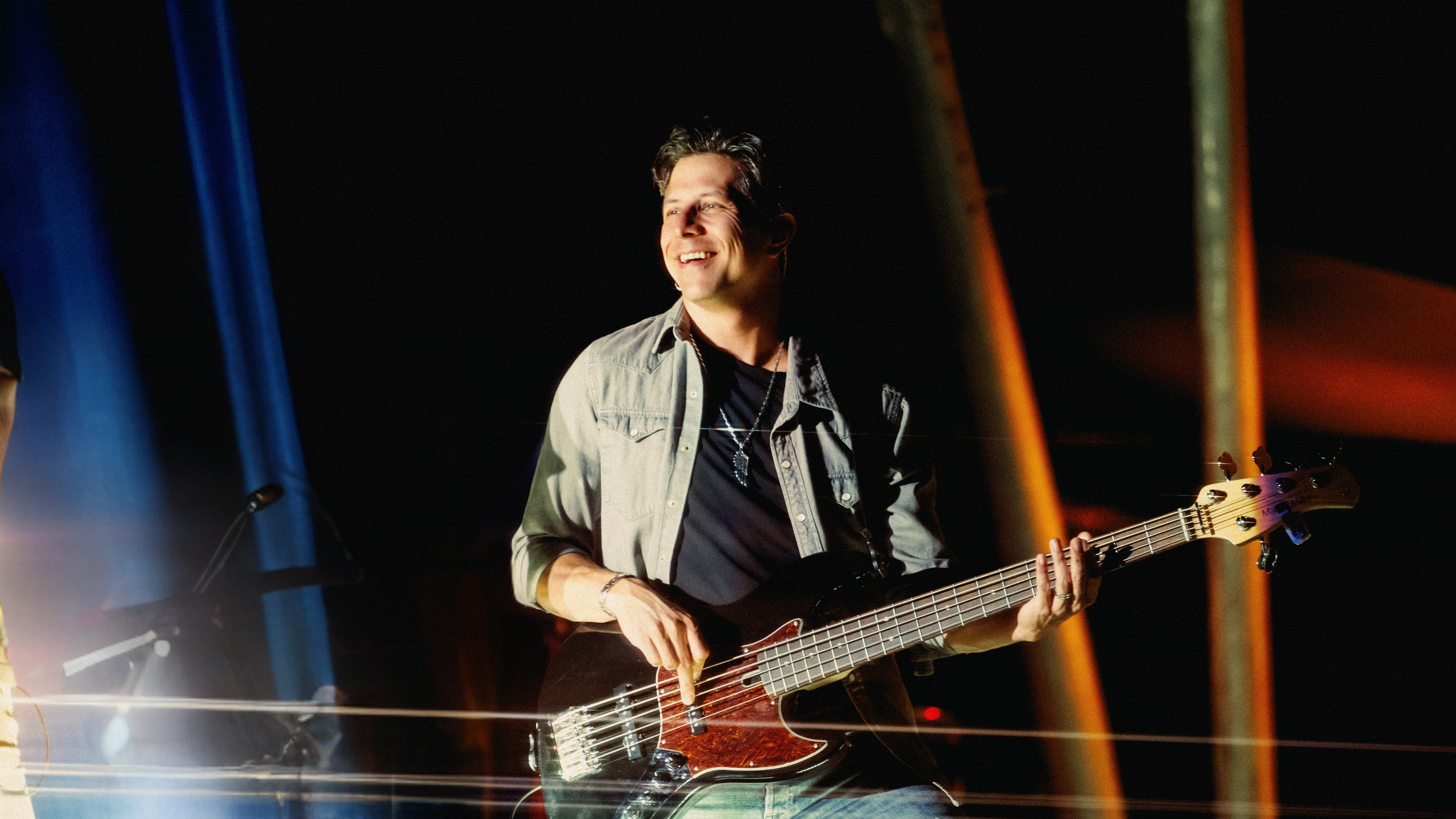 Justin Kudding playing bass guitar on stage with dark background