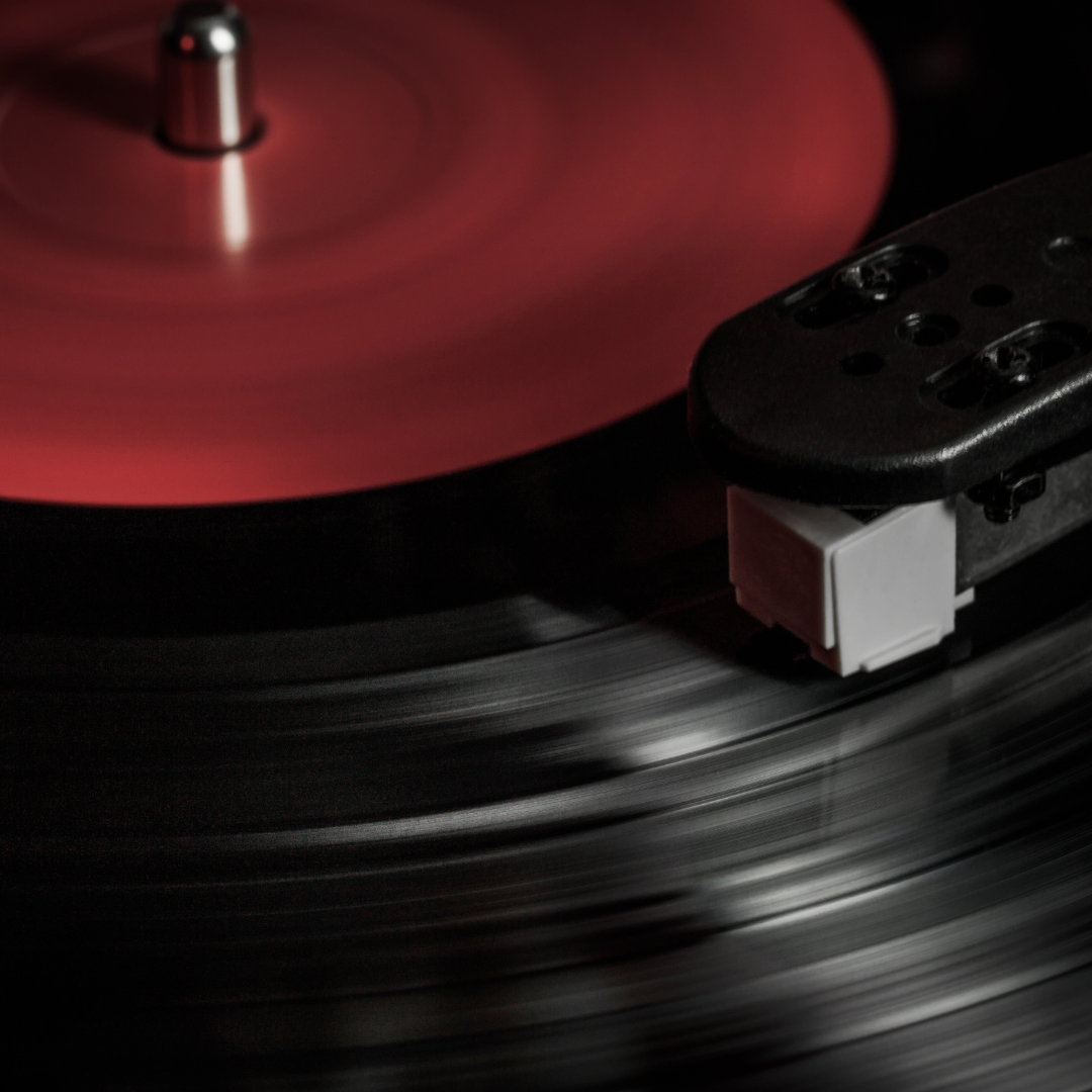 Close up of a red and black record playing on a record player.