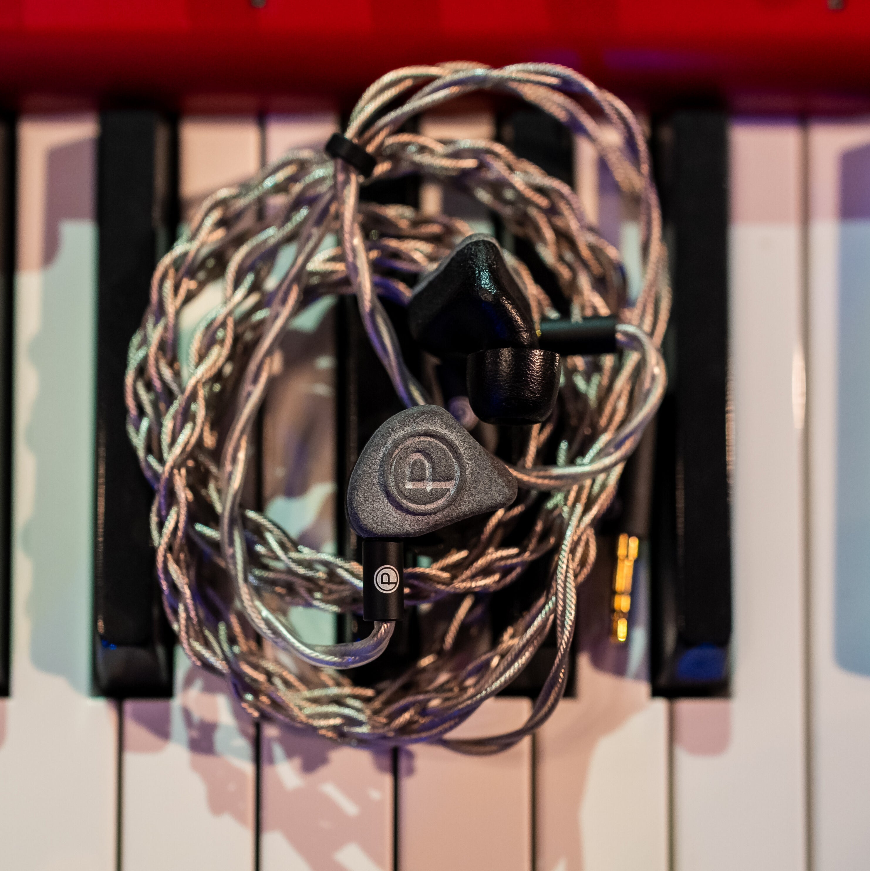 IEMs and cord spun in circle resting on piano keys.