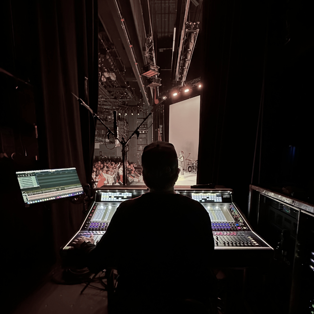 Sound tech sitting in front of console to the right of stage.