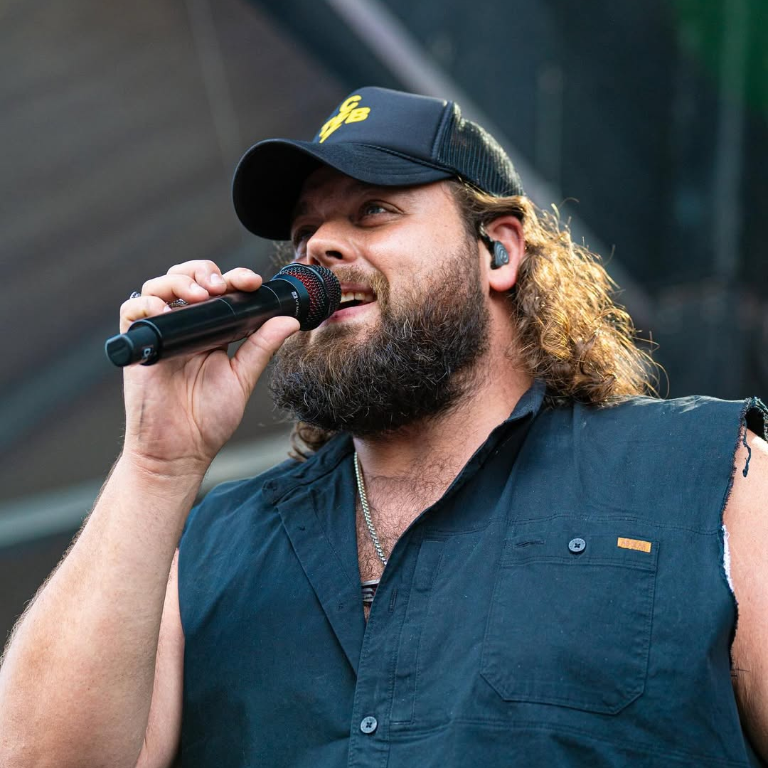 Man in hat sings with a microphone.