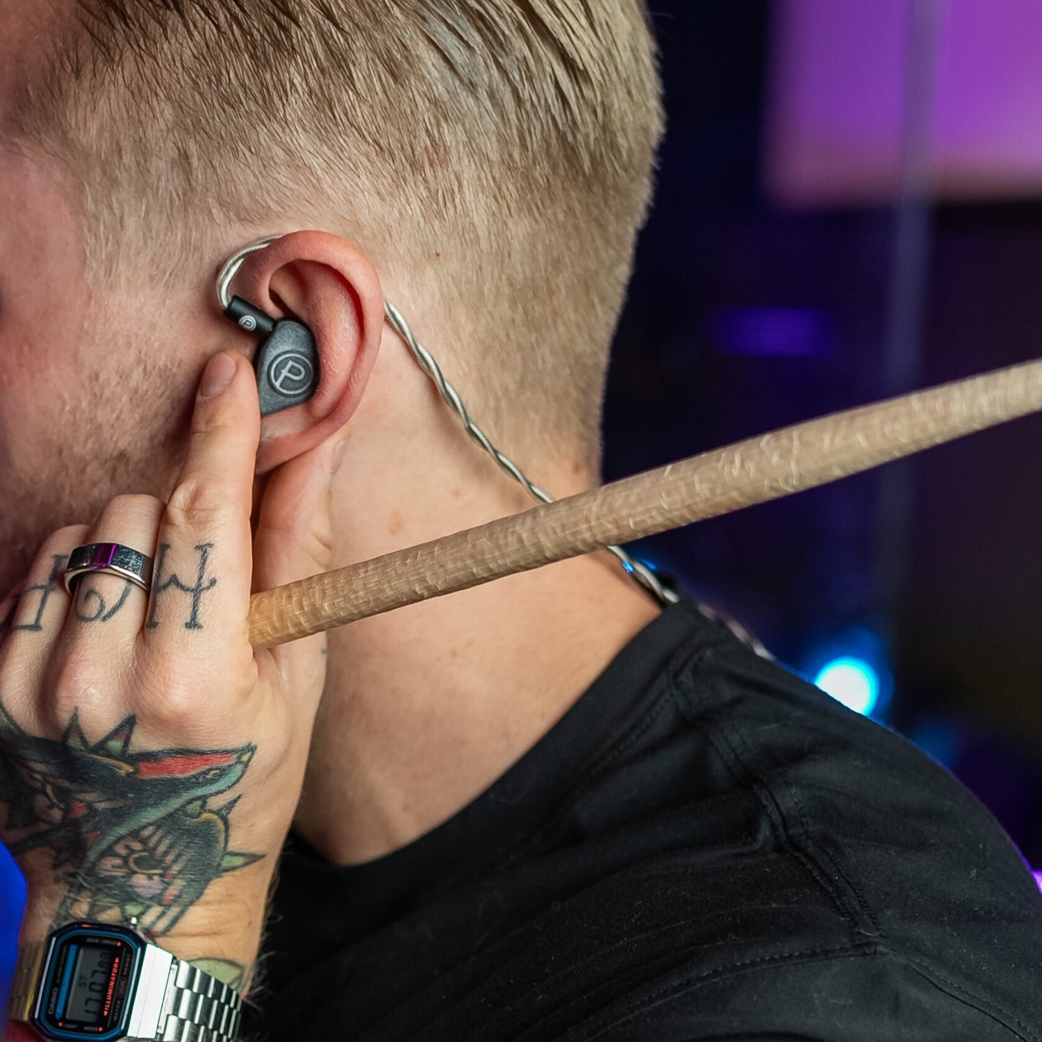Man inserting Plunge Audio IEM into ear holding drum stick.