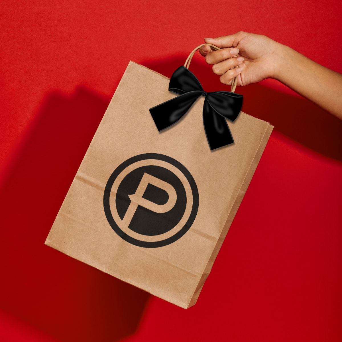 Branded Plunge Audio kraft paper bag on red background.