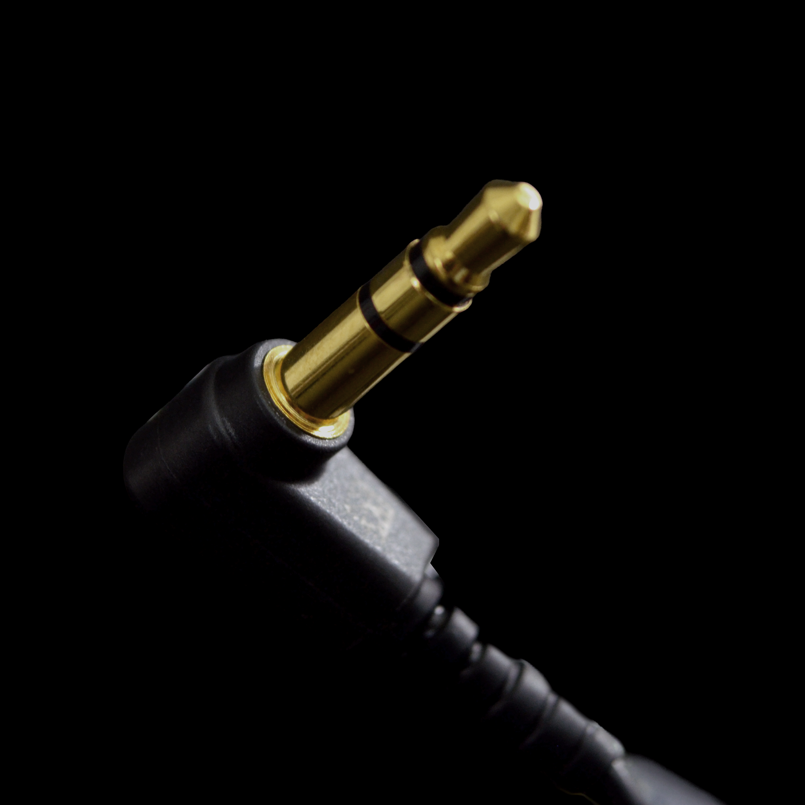 Close-up of a black audio cable with a gold connector on a black background
