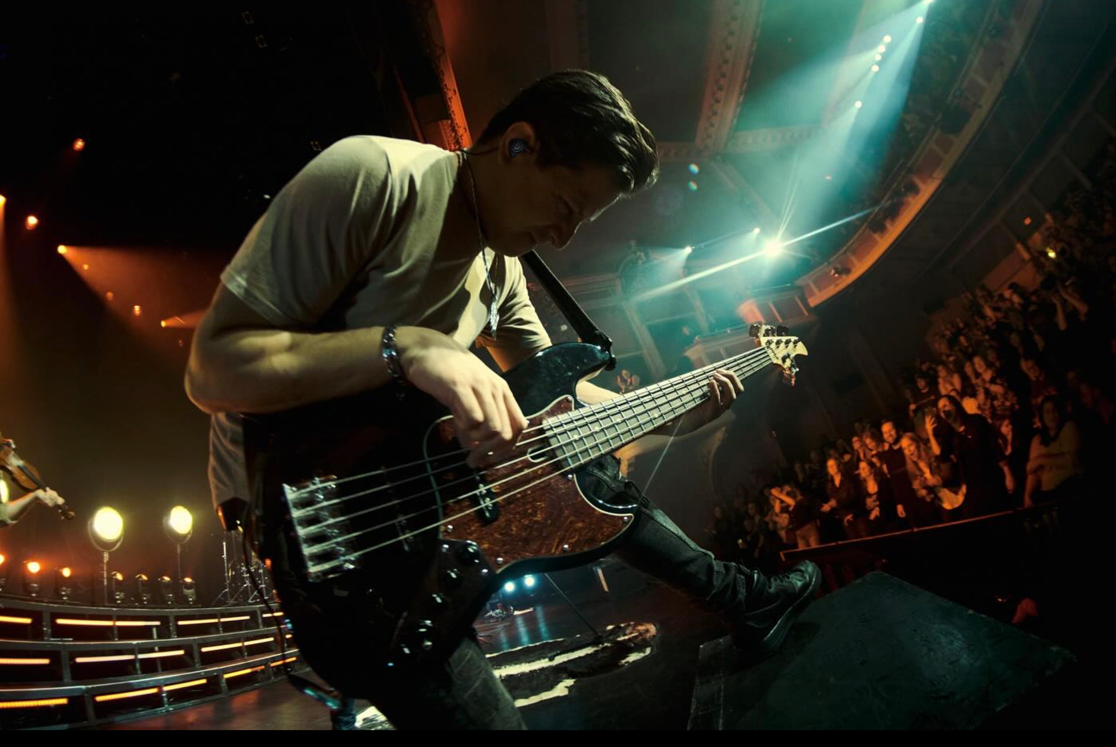 Justin Kudding wearing IEMs and playing bass during live performance with a fish eye effect.