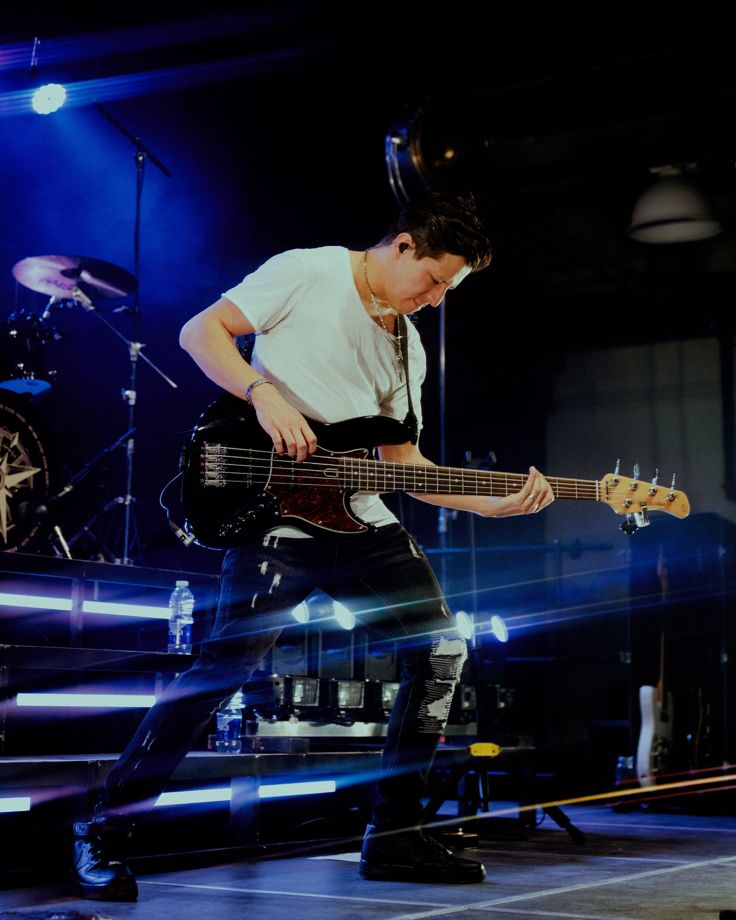 Justin Kudding wearing IEMs and playing bass during live performance.